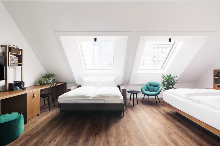 A family room with two double beds and sloping roof in a hotel in Vienna